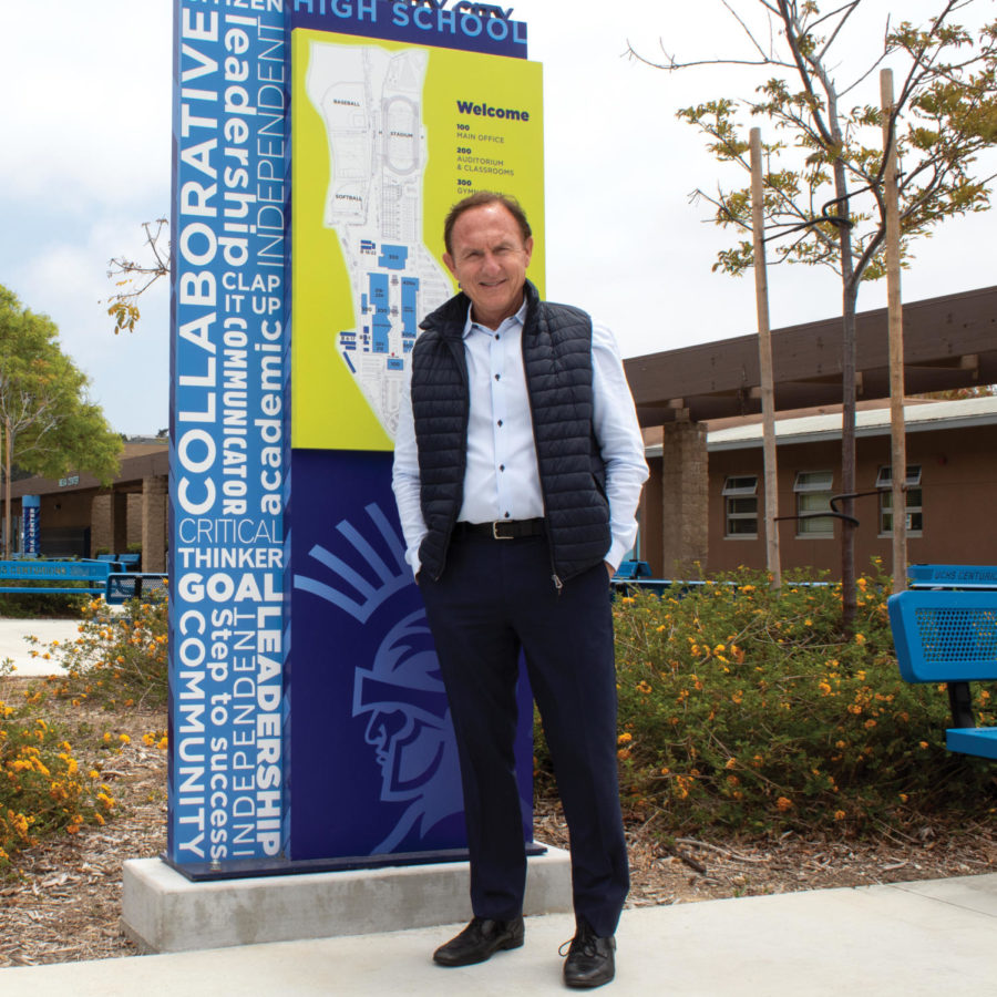 Olivero stands with the Welcome sign in the quad.