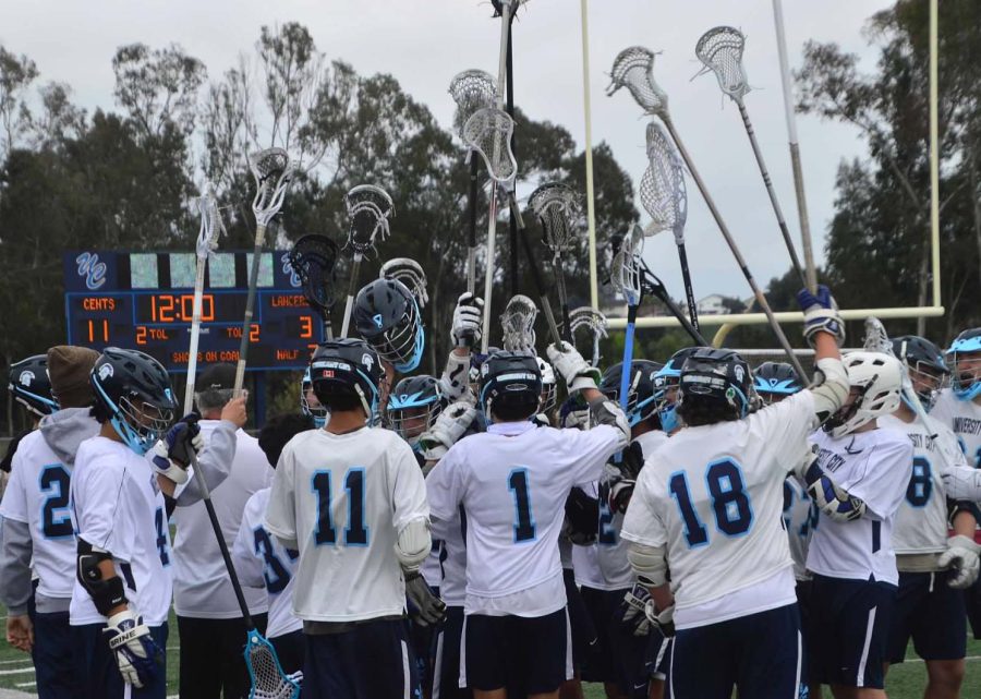 The UC Boys Lacrosse Team raise their sticks to get pumped to finish their game.