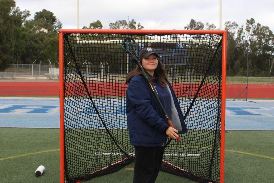 Coach Lizzy Des Enfants posing in front of the lacrosse goal.