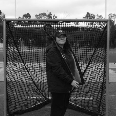 Coach Lizzy Des Enfants posing in front of the lacrosse goal.