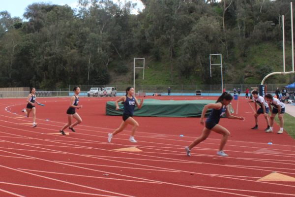 UC Highs girls competing in a 4x100 meter relay race during a track meet.